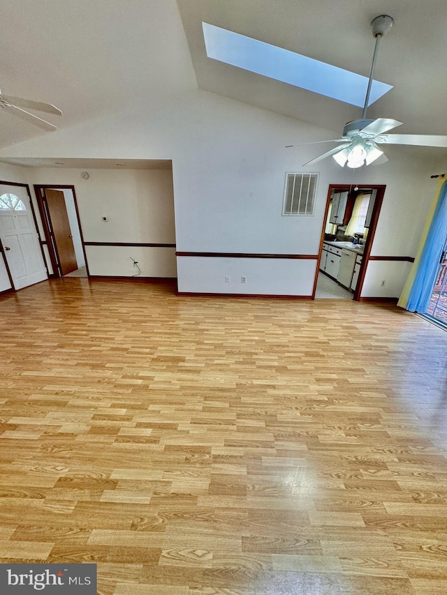 unfurnished living room with ceiling fan, light wood-type flooring, high vaulted ceiling, and a skylight