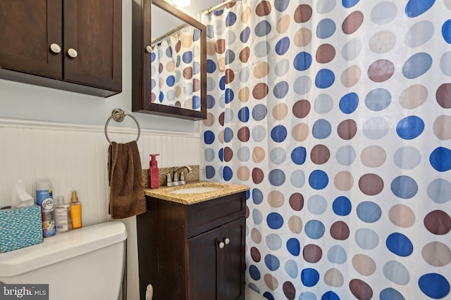 bathroom featuring vanity, wood walls, toilet, and walk in shower