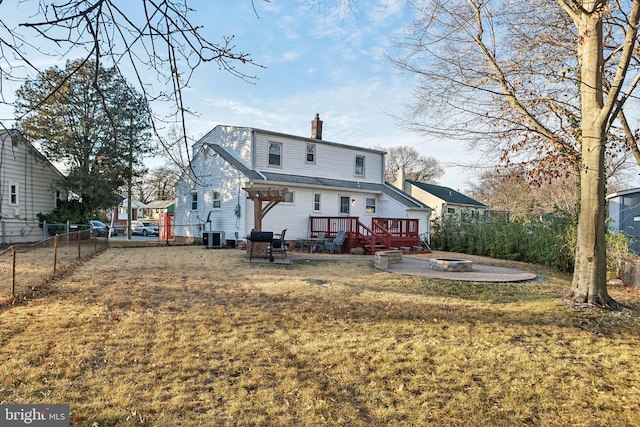 back of house featuring central AC, a yard, a deck, and an outdoor fire pit