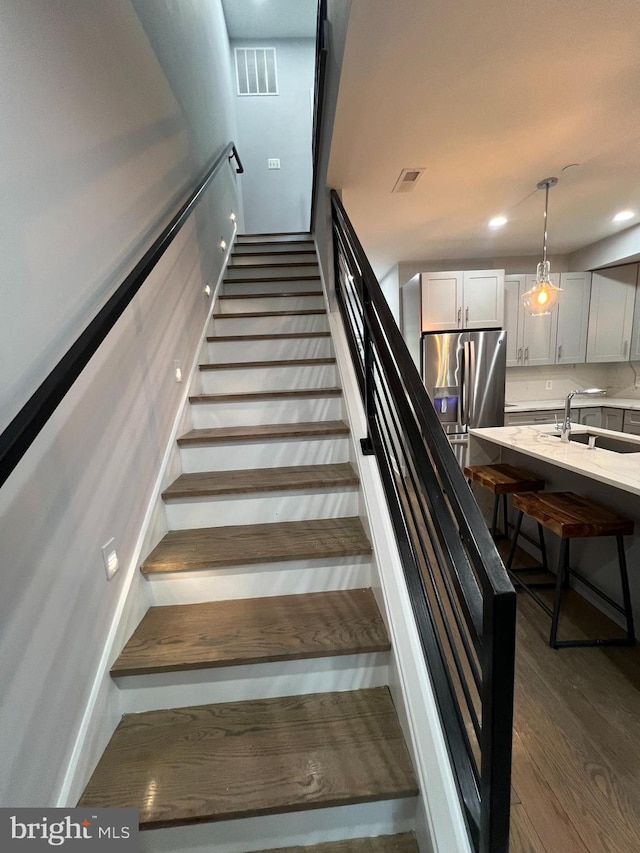 staircase featuring hardwood / wood-style flooring and sink