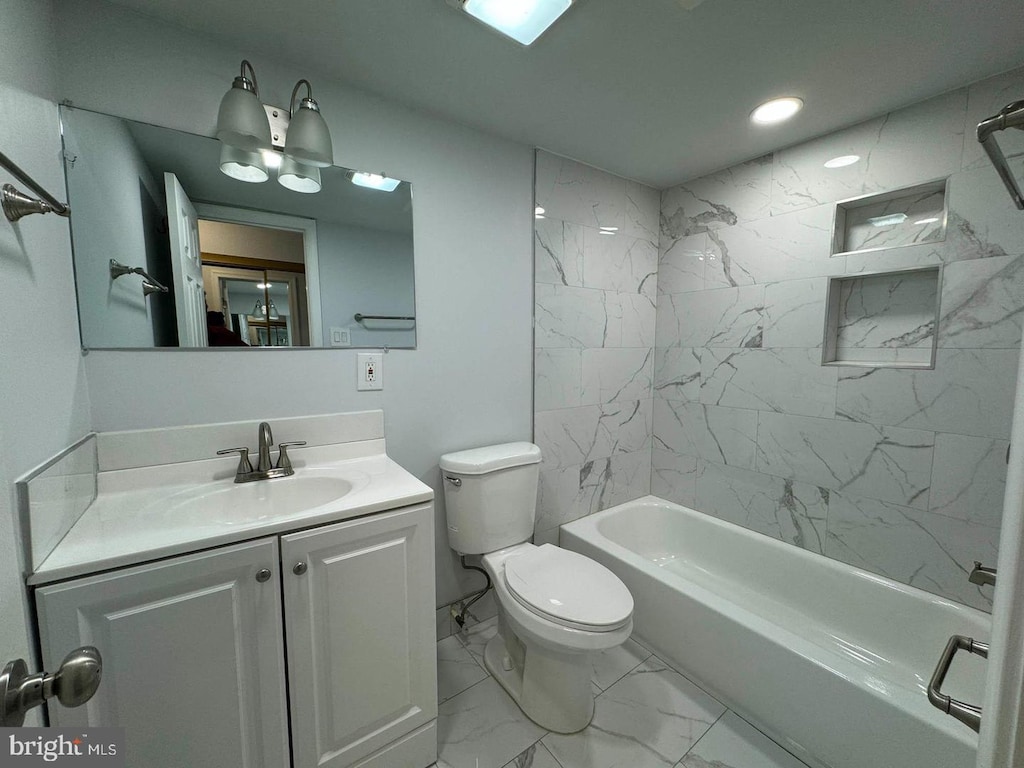 full bathroom featuring vanity, tiled shower / bath combo, and toilet