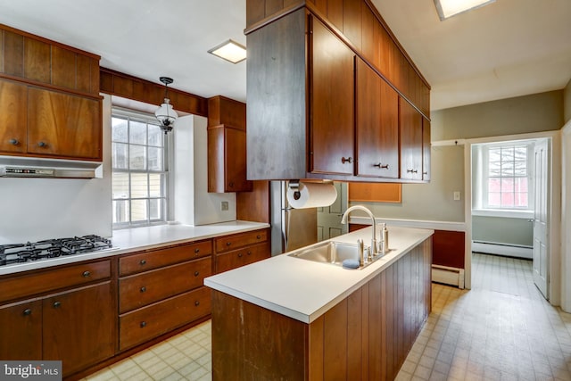 kitchen with hanging light fixtures, sink, an island with sink, and a baseboard radiator