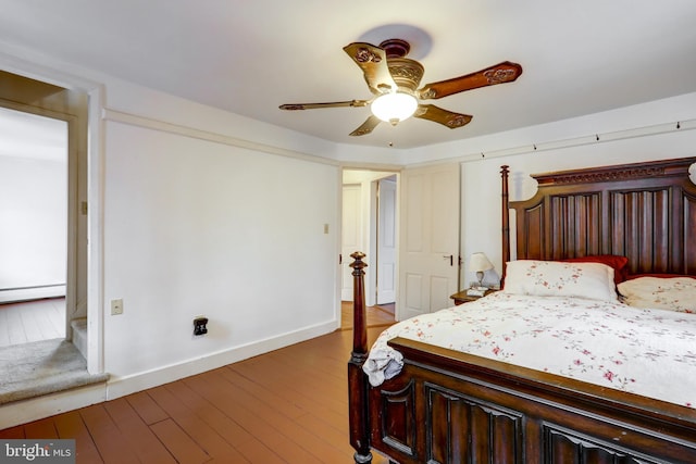 bedroom featuring hardwood / wood-style floors, ceiling fan, and a baseboard heating unit