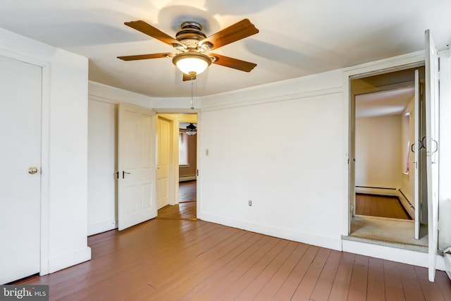 unfurnished bedroom with baseboard heating, ceiling fan, and dark wood-type flooring