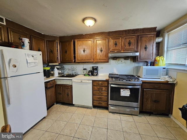 kitchen with light tile patterned floors, white appliances, and sink