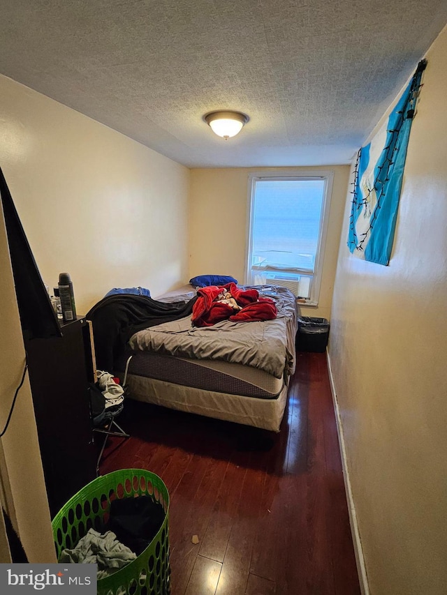 bedroom with dark hardwood / wood-style floors and a textured ceiling