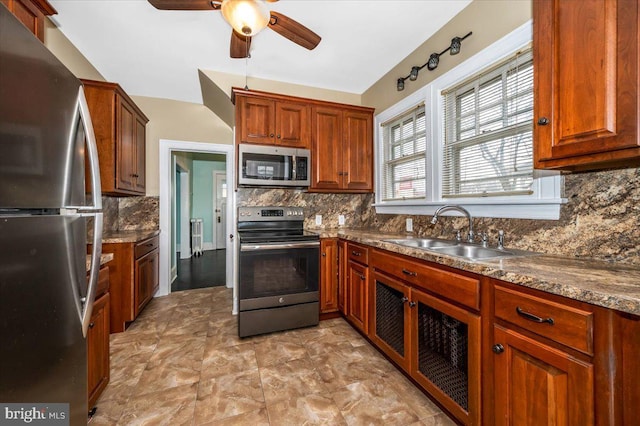 kitchen with tasteful backsplash, stainless steel appliances, ceiling fan, sink, and stone counters