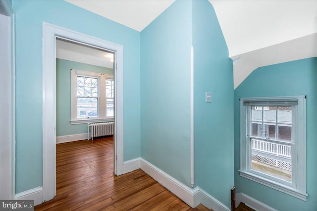 hallway with radiator, hardwood / wood-style floors, and lofted ceiling