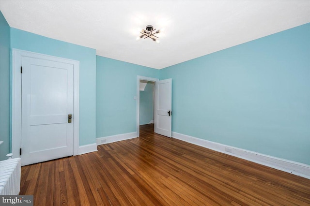 unfurnished bedroom featuring radiator and dark hardwood / wood-style floors