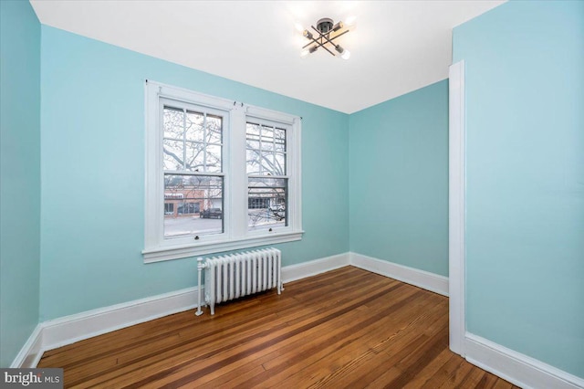 empty room with radiator heating unit and hardwood / wood-style flooring