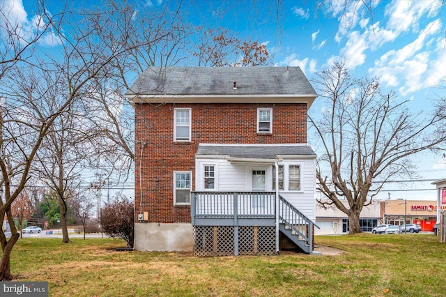 back of property featuring a deck and a lawn