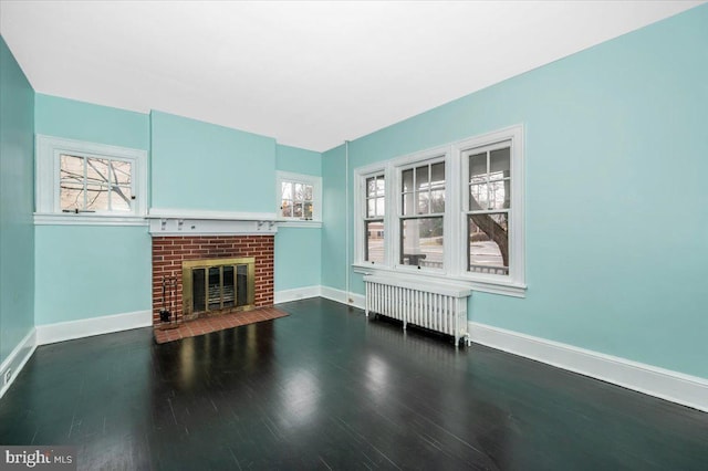 unfurnished living room featuring a fireplace, radiator heating unit, dark hardwood / wood-style floors, and plenty of natural light