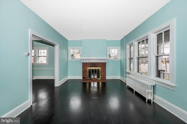 living room featuring hardwood / wood-style flooring, radiator heating unit, and a brick fireplace