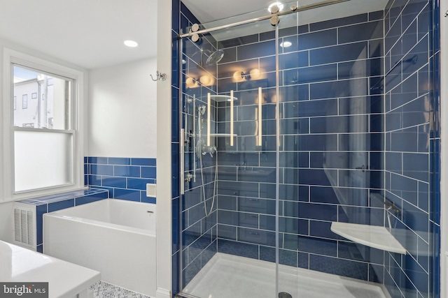 bathroom with separate shower and tub and tile walls