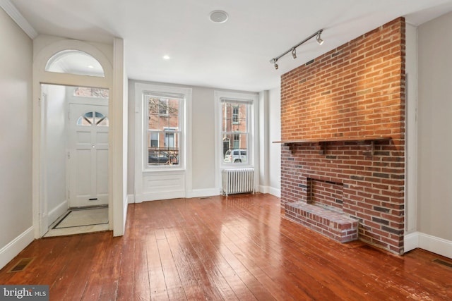 foyer entrance featuring radiator, wood-type flooring, and track lighting