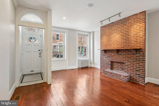 foyer with radiator heating unit, rail lighting, and hardwood / wood-style flooring