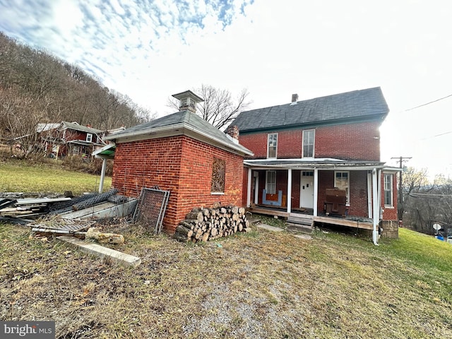 rear view of property featuring a lawn and a porch