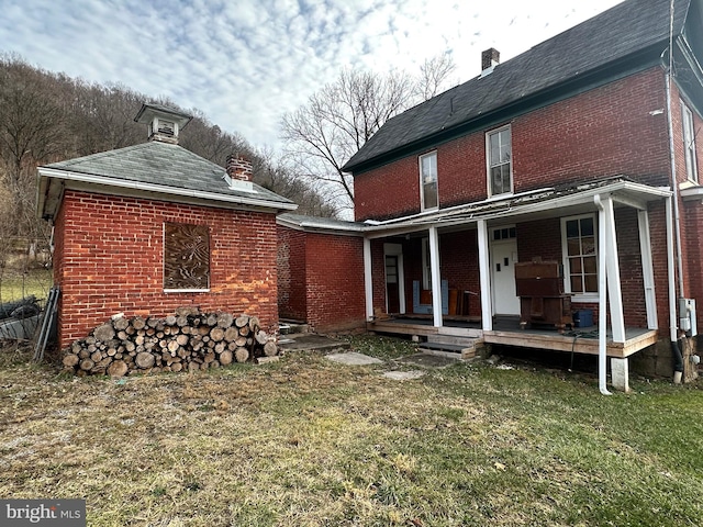 rear view of house featuring a porch and a yard