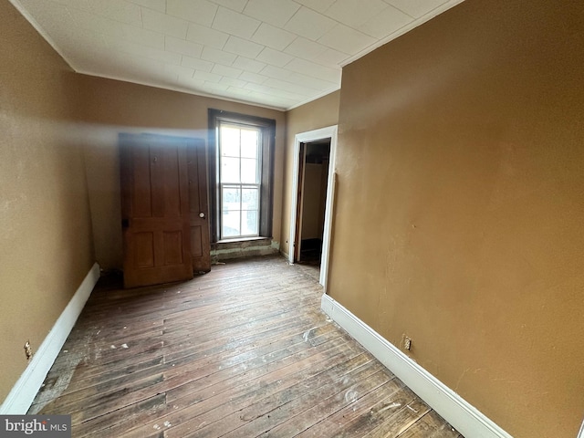 unfurnished room featuring dark wood-type flooring and ornamental molding