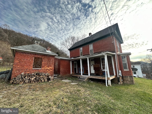 rear view of property featuring a porch and a lawn