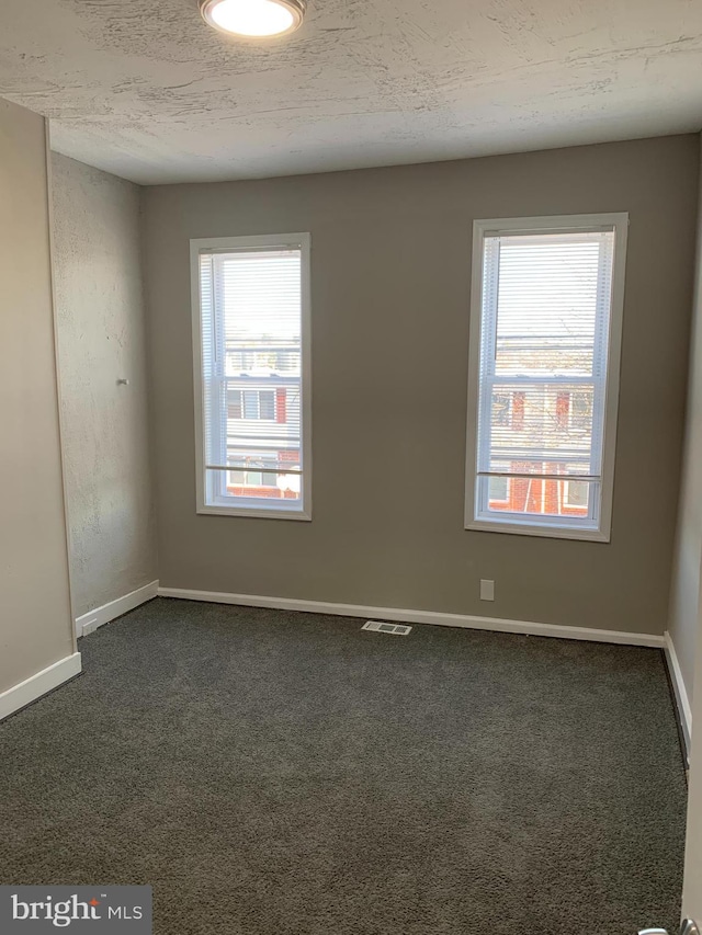 carpeted spare room with a textured ceiling