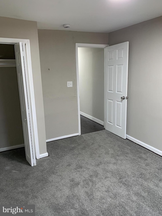 unfurnished bedroom with dark colored carpet and a closet