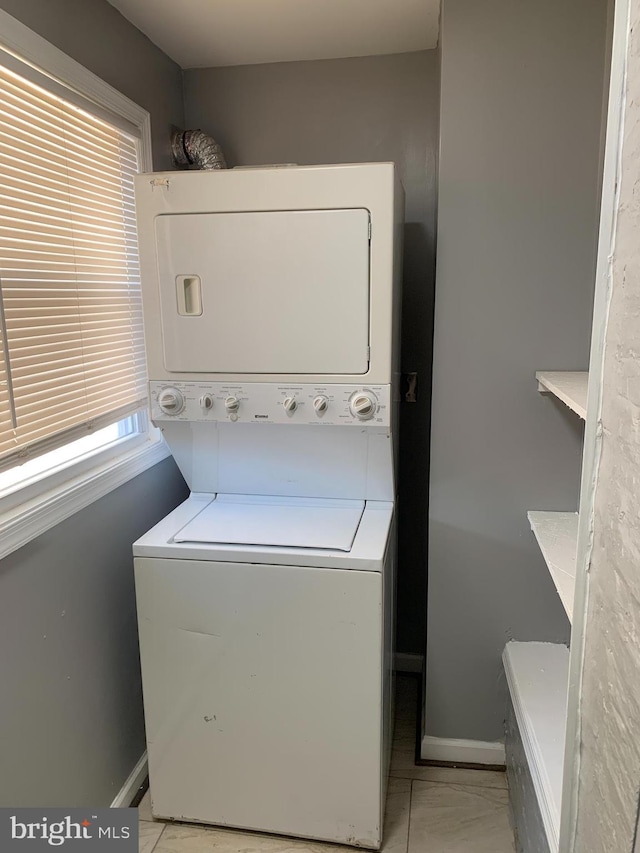 laundry room with stacked washer and dryer and light tile patterned floors