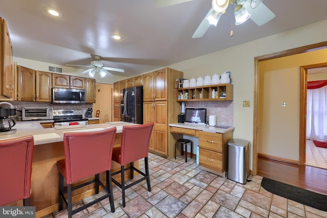 kitchen featuring kitchen peninsula, a breakfast bar area, appliances with stainless steel finishes, and tasteful backsplash