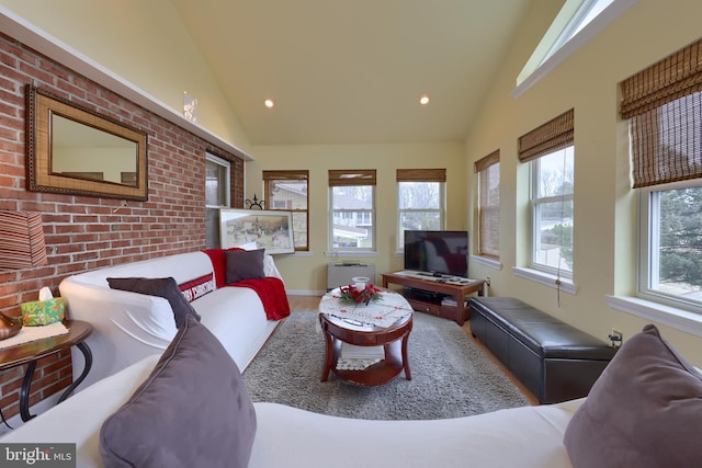 living room featuring lofted ceiling and brick wall