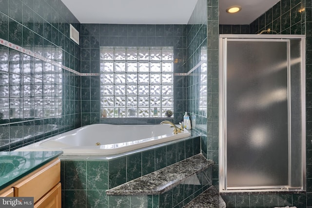 bathroom featuring vanity, separate shower and tub, and tile walls