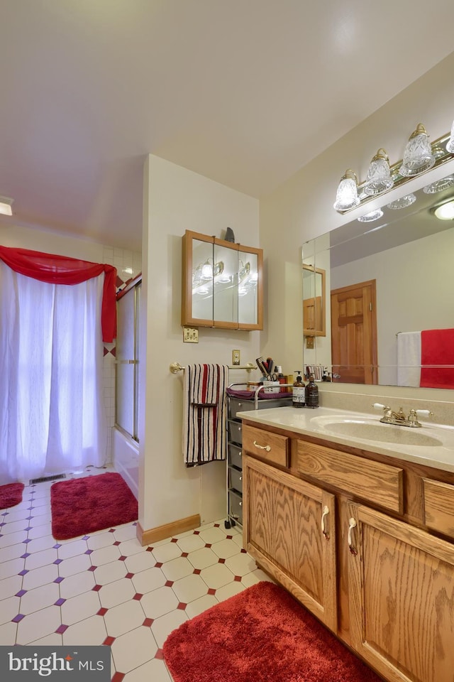 bathroom featuring vanity and bath / shower combo with glass door