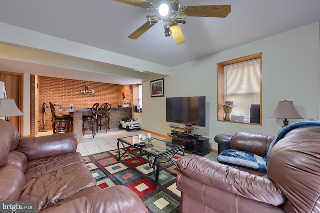 living room featuring bar, ceiling fan, light tile patterned flooring, and brick wall