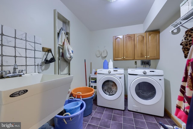 laundry room with washer and dryer, dark tile patterned floors, cabinets, and sink