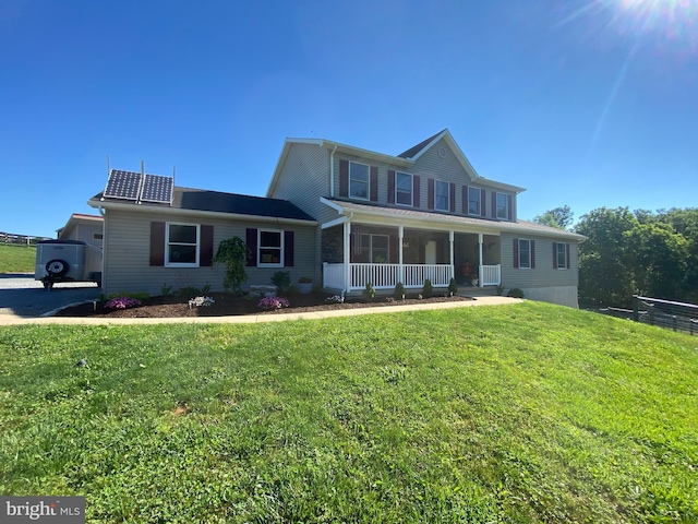 view of front of home with solar panels, covered porch, and a front yard