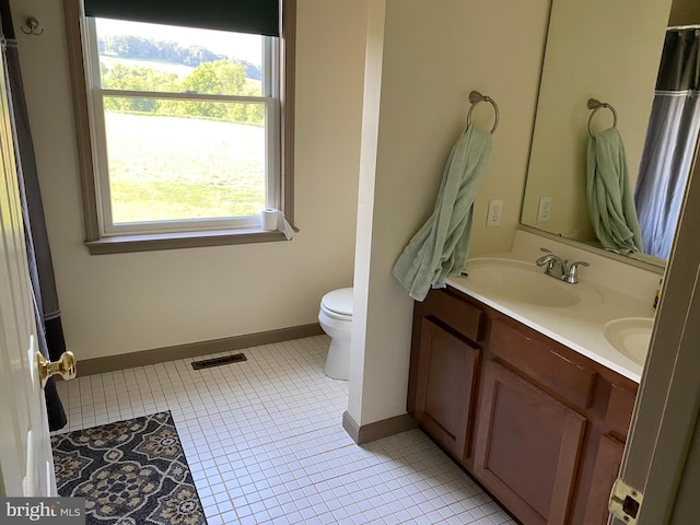 bathroom with toilet, vanity, and tile patterned floors