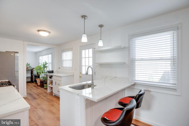 kitchen with pendant lighting, a breakfast bar, kitchen peninsula, sink, and white cabinetry