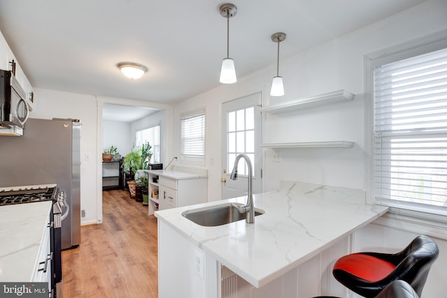 kitchen with sink, light stone countertops, white cabinetry, kitchen peninsula, and stainless steel appliances