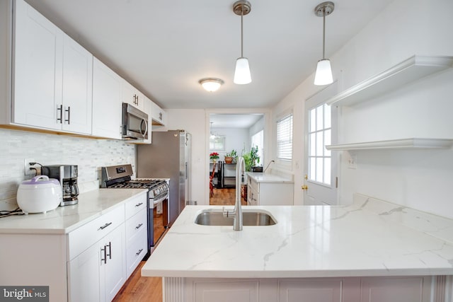 kitchen featuring hanging light fixtures, sink, white cabinets, and stainless steel appliances