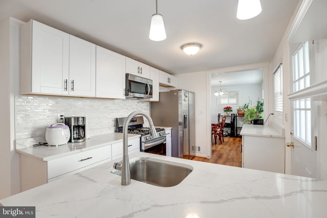 kitchen featuring decorative light fixtures, light stone counters, white cabinetry, and appliances with stainless steel finishes