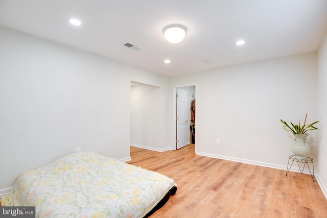 bedroom with a walk in closet and light hardwood / wood-style floors