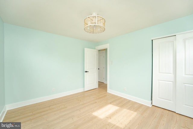 unfurnished bedroom featuring light hardwood / wood-style floors, an inviting chandelier, and a closet