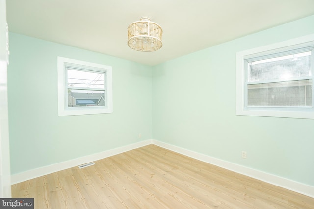 unfurnished room with light hardwood / wood-style flooring and a chandelier