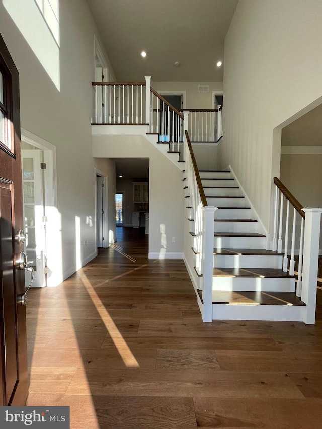 staircase with wood-type flooring and a high ceiling