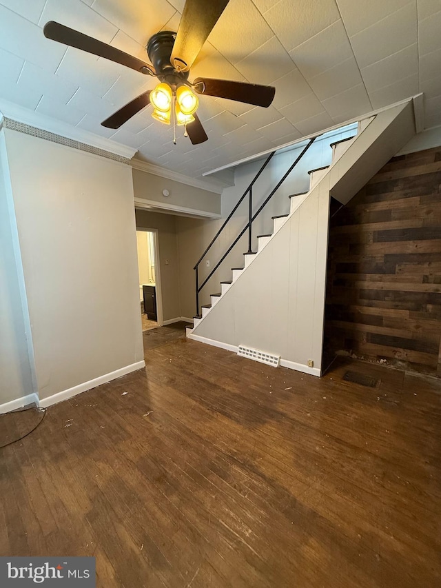 basement with ceiling fan, crown molding, and dark wood-type flooring