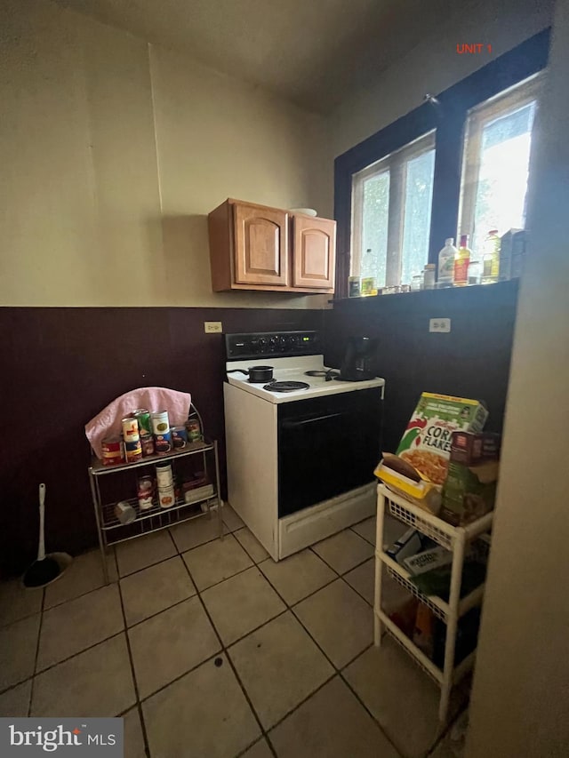 kitchen featuring light tile patterned flooring, light brown cabinetry, and electric stove