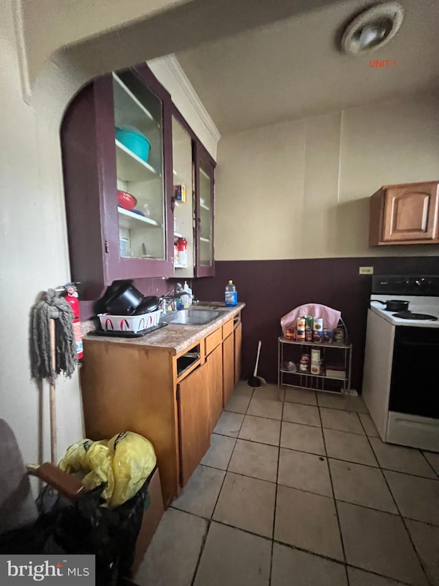 kitchen with white electric range oven, light tile patterned floors, and sink