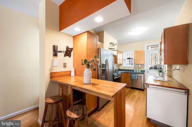 kitchen with kitchen peninsula, light wood-type flooring, and appliances with stainless steel finishes