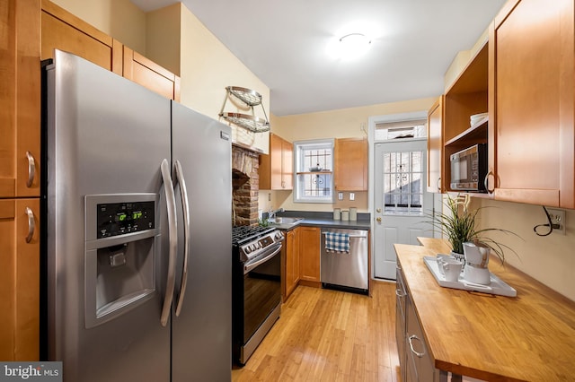 kitchen featuring butcher block countertops, sink, light wood-type flooring, and stainless steel appliances