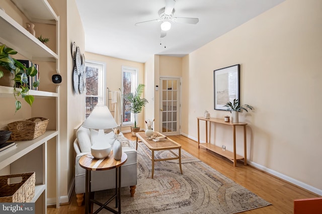 sitting room featuring built in shelves, ceiling fan, and hardwood / wood-style floors