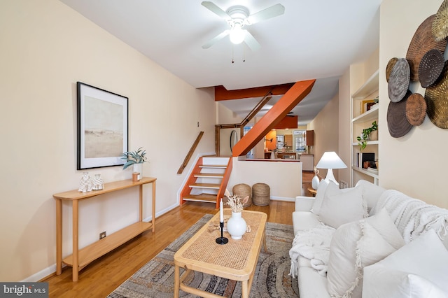 living room featuring wood-type flooring, built in features, and ceiling fan